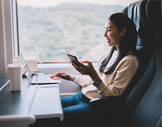 Woman using the internet on board the train to use her phone and computer